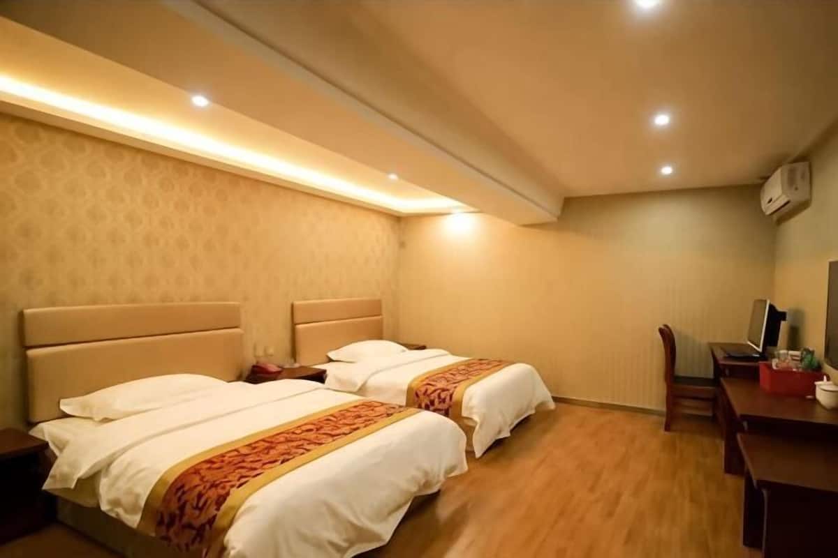 A hotel room with two beds, a desk, and a chair.