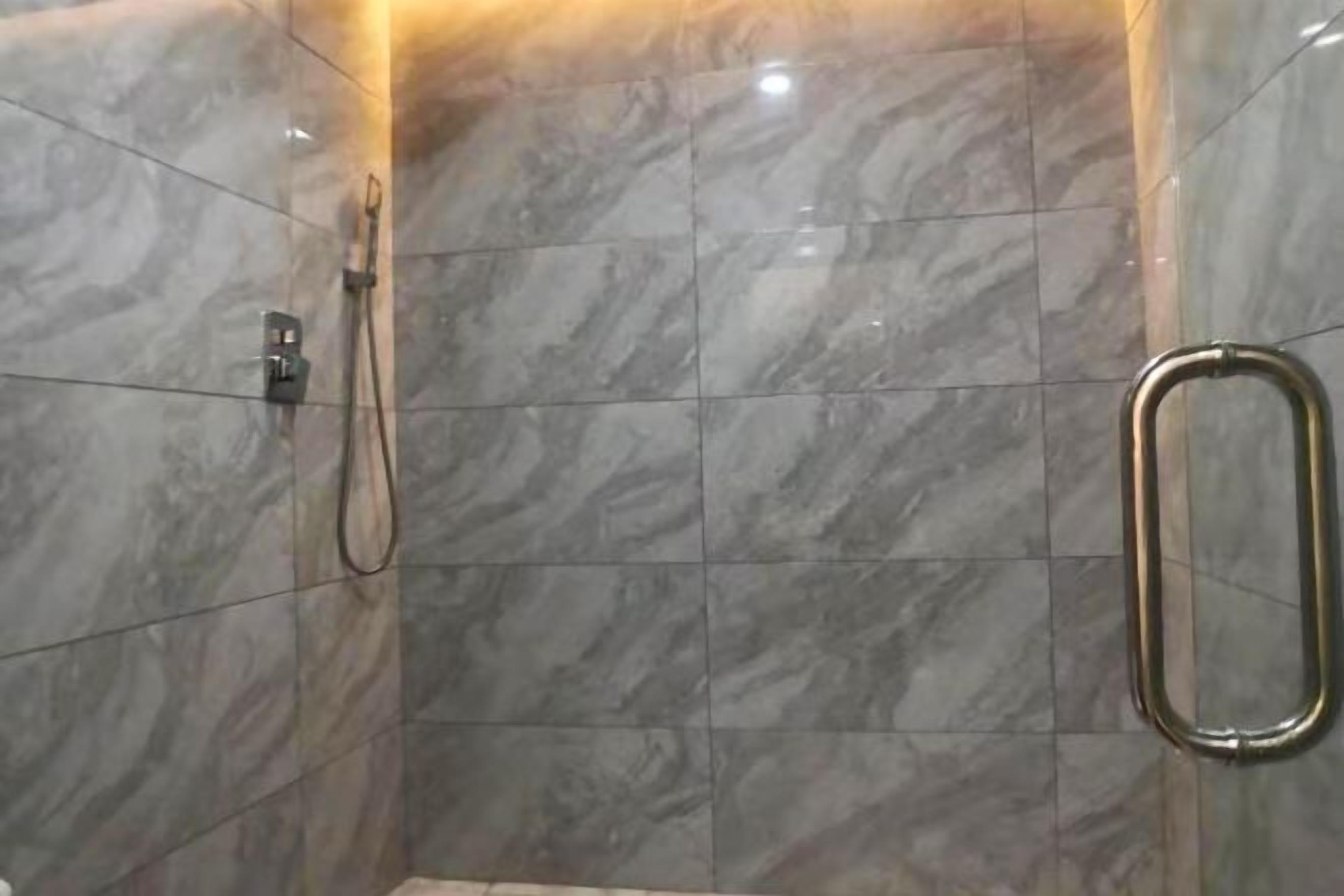 Una ducha con cabezal de ducha manual y barra de apoyo.