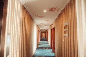 A hotel corridor with striped walls, a patterned carpet, and a ceiling with floral designs. - Yichun Mantu Hotel (Yichun)