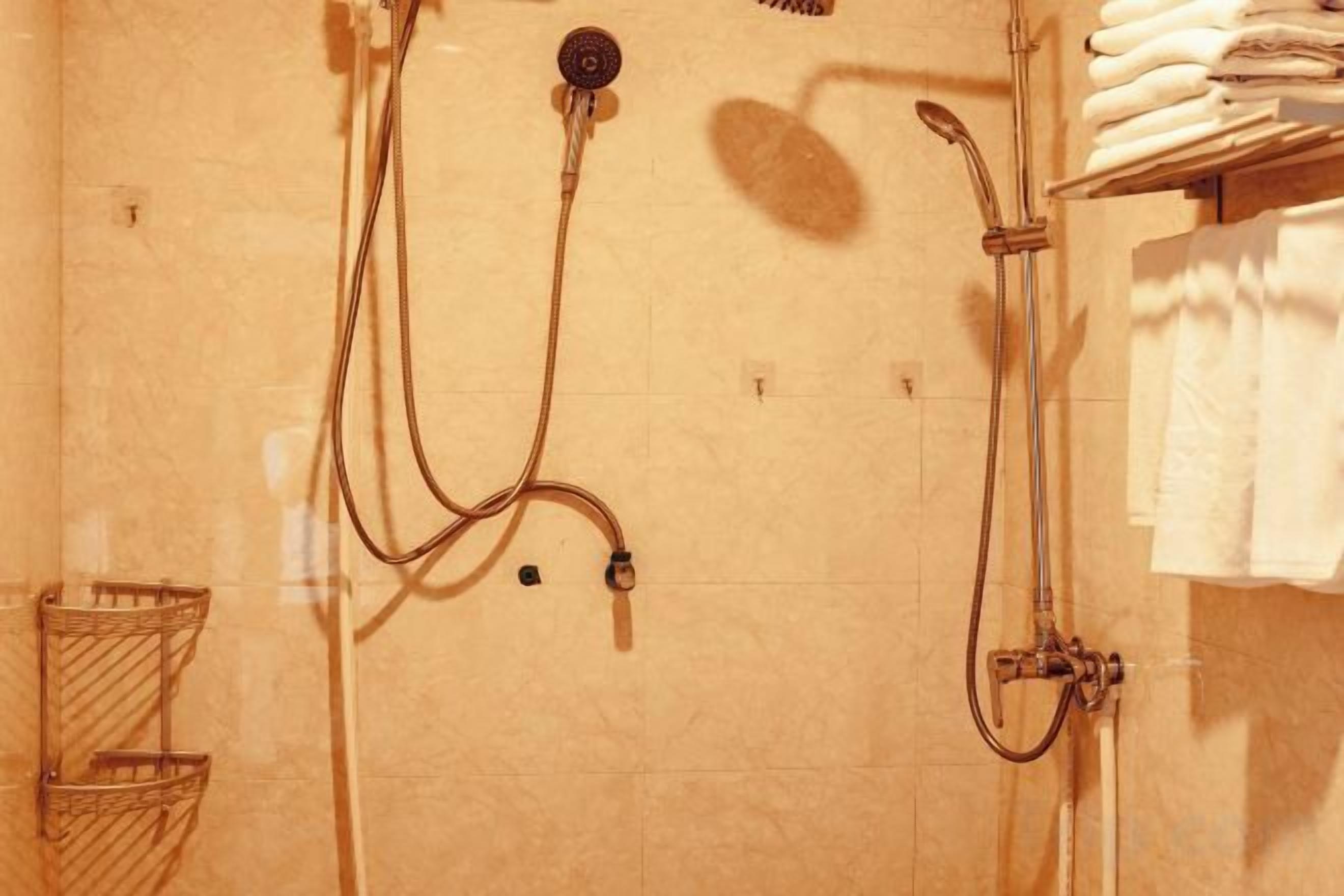 A bathroom with a shower, a towel rack, and a towel dispenser.