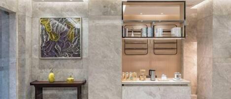 A modern kitchen with marble countertops, a wooden cabinet, and a small table with decorative items.