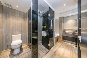 Un baño moderno con inodoro, cabina de ducha de vidrio y zona de lavamanos.