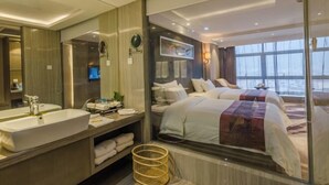A modern hotel room with a large bed, a separate sitting area, a large window with a view, a bathroom with a sink and mirror, and a television. - West Wealth Borrman （Ningde Wanda Plaza） (Ningde)