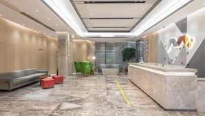 A modern lobby with a reception desk, seating area, and a large plant. - West Wealth Borrman （Ningde Wanda Plaza） (Ningde)