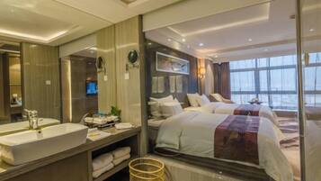 Una habitación de hotel moderna con una cama grande, un baño separado con bañera y un amplio ventanal con vistas a la ciudad.