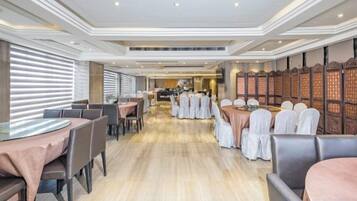 A spacious restaurant with a long counter, multiple tables, and a high ceiling with recessed lighting.