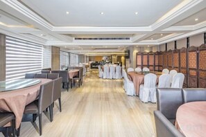 Un restaurant spacieux avec un long comptoir, de nombreuses tables et un plafond haut doté d’un éclairage encastré.