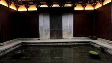 A traditional Japanese-style room with a tatami mat floor, a wooden door, and a small stone basin.