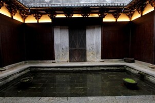 A traditional Japanese-style room with a tatami mat floor, a wooden door, and a small stone basin.