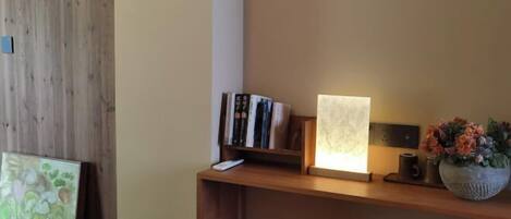 Una estantería de madera con libros, un cuadro enmarcado y un jarrón con flores.