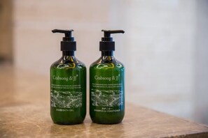 Two bottles of Crabsong & JJ bath gel and shampoo & conditioner on a marble surface. - Xinxing Business Hotel (Wuyishan)