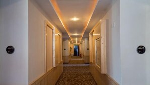 A hotel hallway with wooden paneling, patterned carpet, and numbered doors. - Xinxing Business Hotel (Wuyishan)