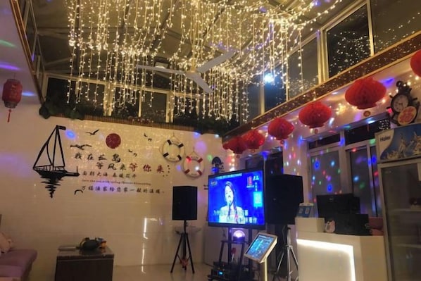Una habitación con televisión, un escritorio y una pared decorada con luces y faroles rojos.