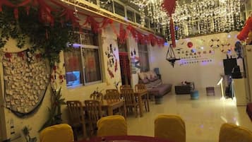 Un comedor con una mesa redonda, sillas y un sofá. Hay luces decorativas y una pared con varios objetos.