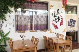 Uma sala de jantar com mesa e cadeiras, uma janela com cortinas e uma parede com detalhes decorativos.