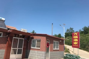 Un edificio con fachada roja y blanca, una puerta visible y un letrero con texto amarillo.