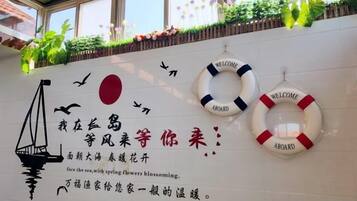 A wall with a nautical theme, including a lifebuoy and a crane illustration, and text in a foreign language.