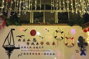 Une chambre avec vue sur la mer, une illustration de navire et des guirlandes lumineuses décoratives.