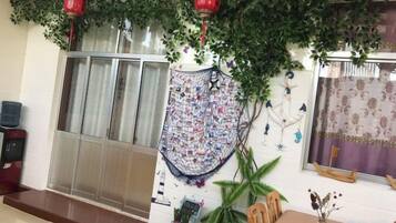 A room with a sliding glass door, a patterned wall hanging, and a potted plant.