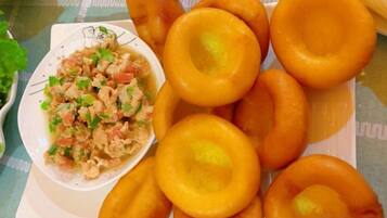 A plate of round, golden-brown fried items with a bowl of chopped vegetables and herbs.