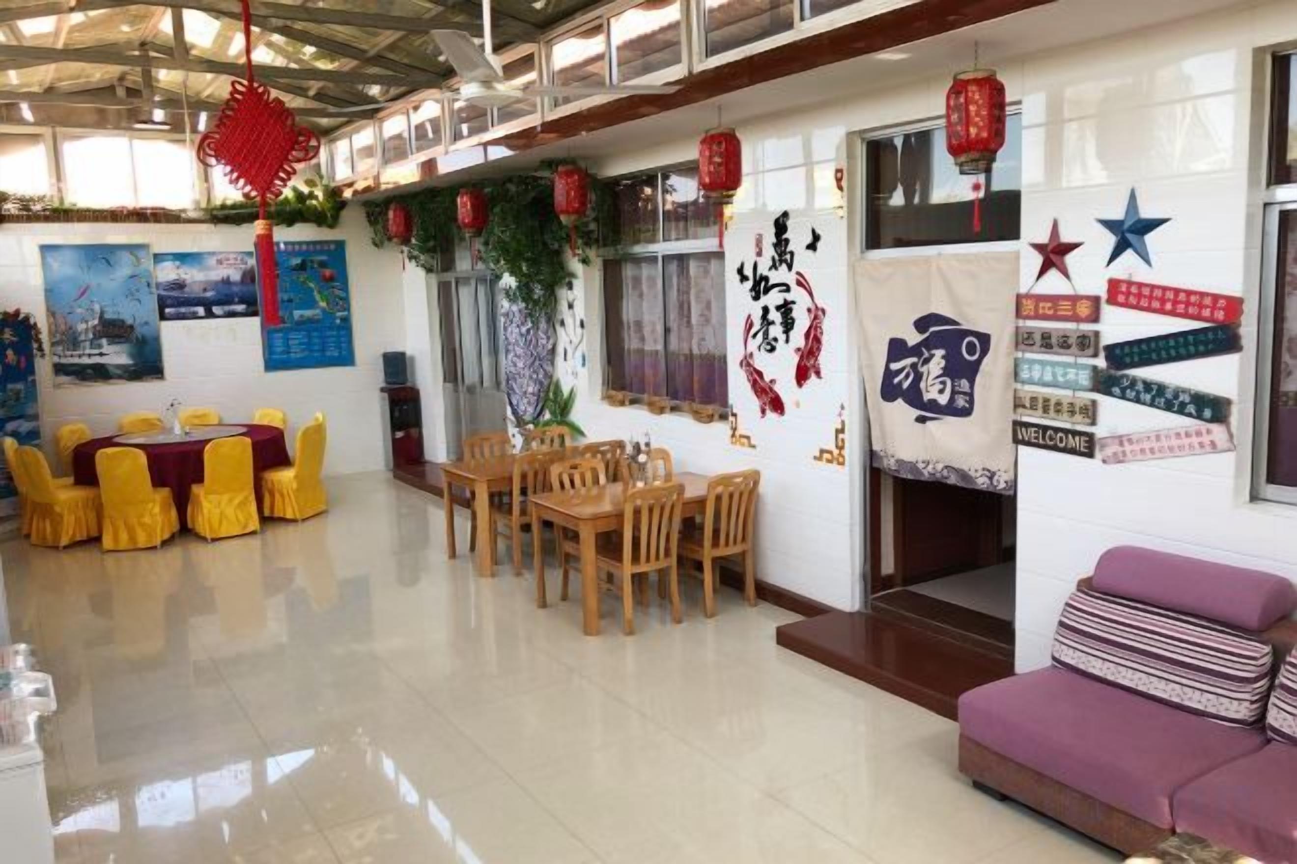 Un espacio de comedor con sillas amarillas y una mesa, un sofá púrpura y faroles rojos.