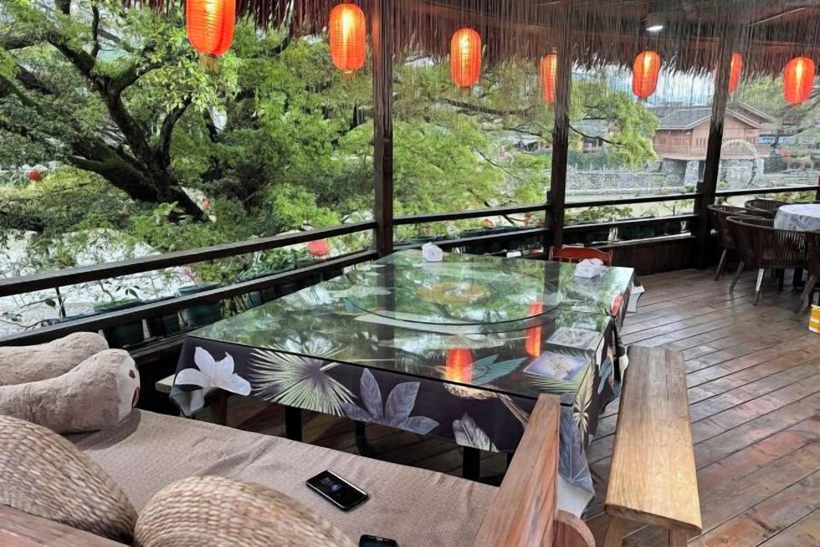Un ristorante con un tavolo in vetro, panche in legno e vista su spazi verdi.