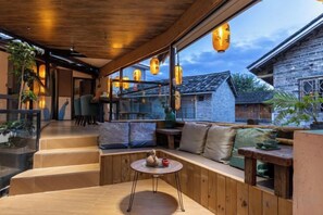 Un interior de madera con una zona de estar, una mesita y lámparas colgantes.