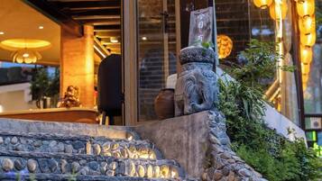 Una escalera de piedra que sube a la entrada de un edificio, con una figura decorativa de león de piedra y un jarrón grande en la parte superior.