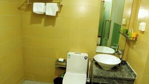Un baño con paredes amarillas, un inodoro blanco, un lavamanos con encimera de mármol y un espejo.