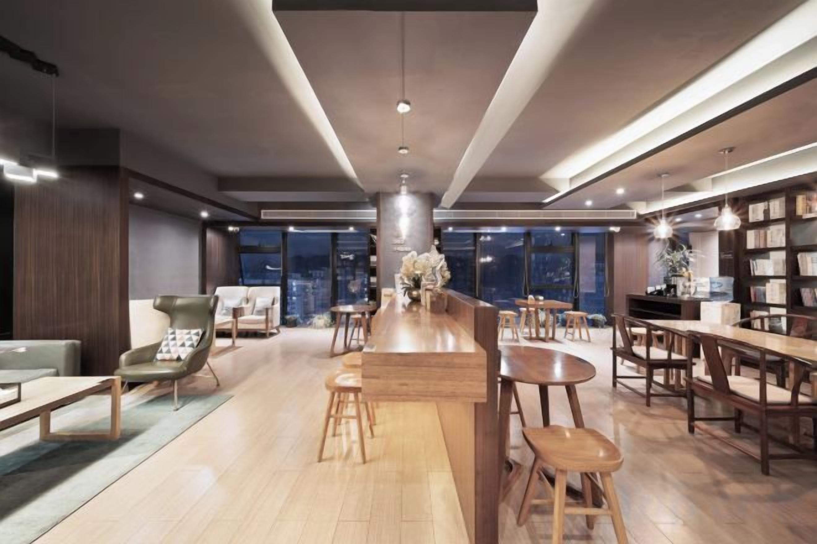 A modern bar area with a central bar, seating arrangements, and a view of the city at night.