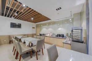 A modern kitchen with a dining area, featuring a large table, chairs, and a built-in oven. - Motel (The Bund, Qipu Road, Tiantong Road Metro Station) (Shanghai)