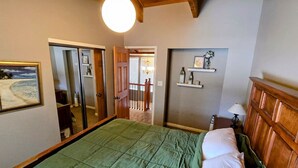 A bedroom with a bed, a nightstand, a mirror, and a shelf with decorative items. - Park Ave Condo #3, Sauna+Hot Tub (Park City)