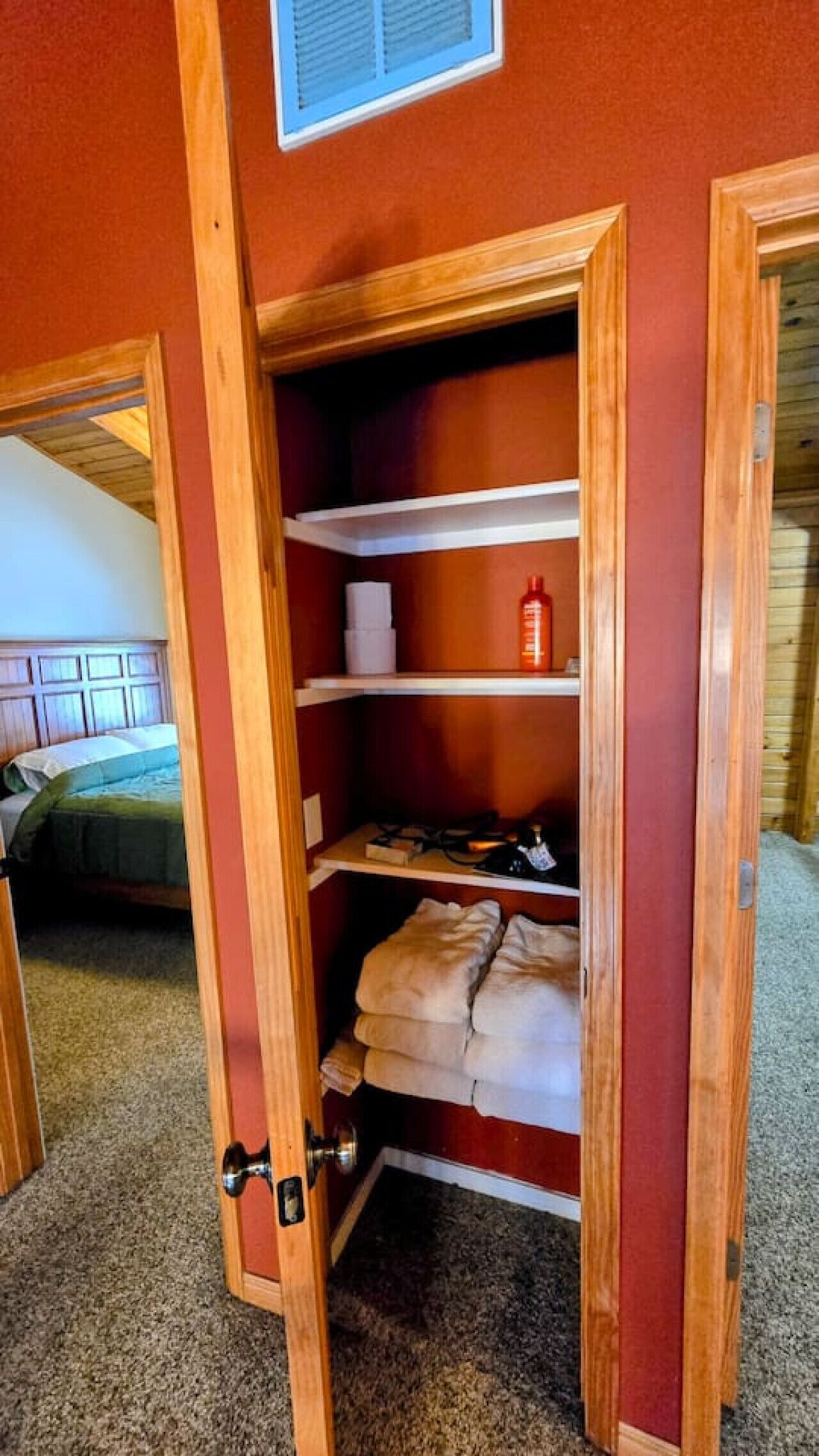 A wooden closet with shelves, a hanging rack, and a fire extinguisher.