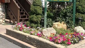 A lodge sign with a contact number, surrounded by a flower bed and a staircase leading to a building. - Park Ave Condo #3, Sauna+Hot Tub (Park City)