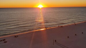 A beach with a sunset over the ocean, a sandy shore, and a few people and benches. - Sunsets on the Gulf!  2nd Floor unit.  Available dates 8/22 - 8/31/26 (Panama City Beach)