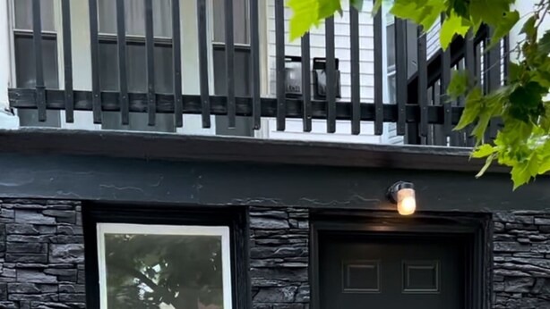A house with a dark front door, a window, and a stone facade.