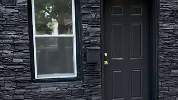 A house with a dark front door, a window, and a stone facade.