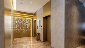A modern elevator interior with a marble floor, a wall-mounted light fixture, and a trash bin. - Starway Hotel (Liaocheng Zhenxing West Road) (Liaocheng)