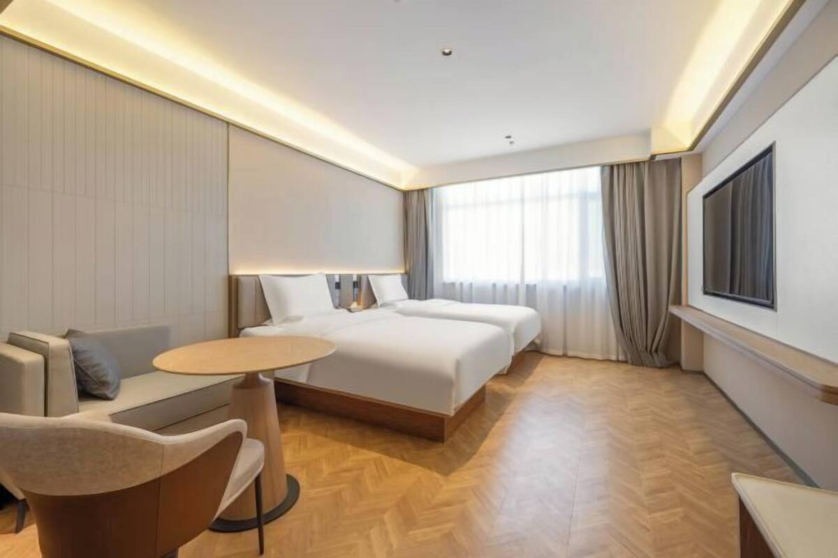 A modern hotel room with a large bed, a sofa, a round table, and a TV.