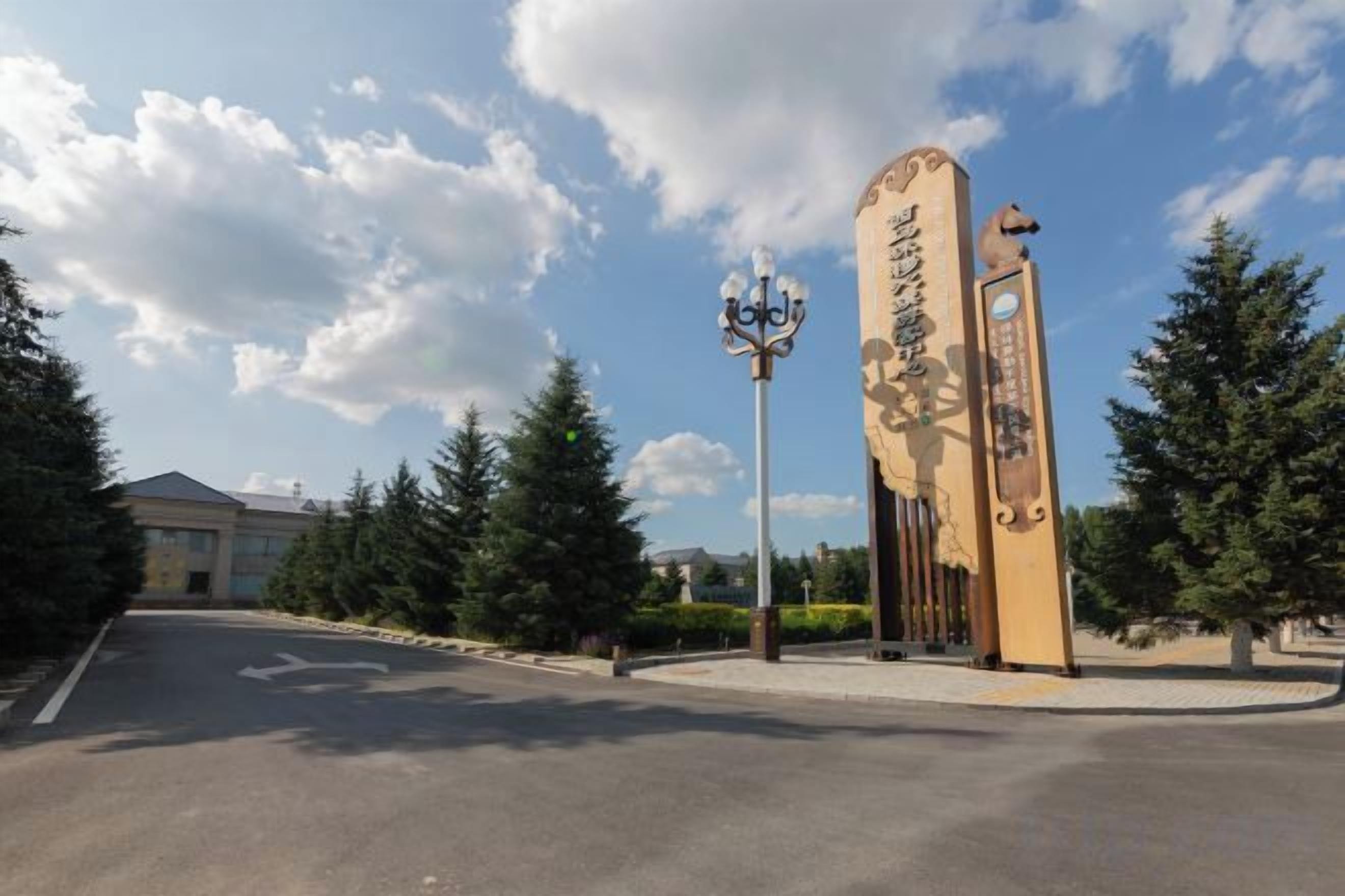 A road leading to a building with a large sign and a street lamp.