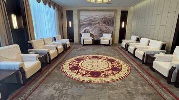 A meeting room with a carpeted floor, a large painting, and multiple chairs arranged for a meeting.