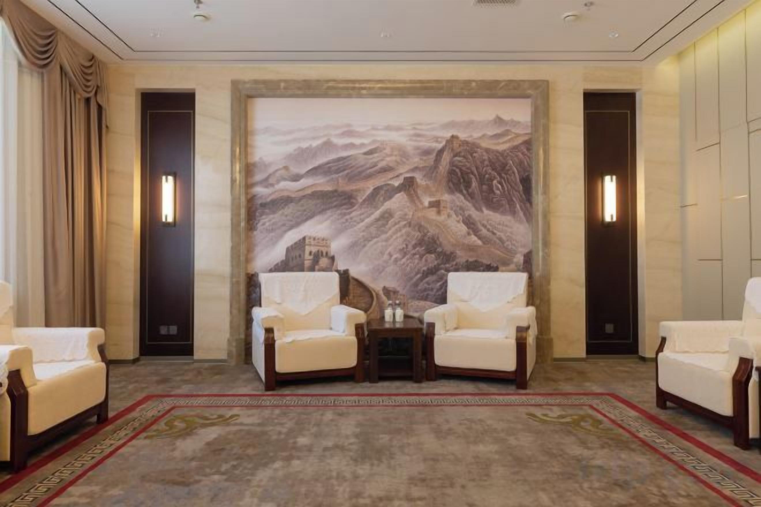 A room with a large wall mural, two armchairs, a small table, and a carpeted floor.