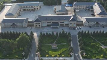 A large, multi-story building with a central courtyard, surrounded by parking areas and greenery.
