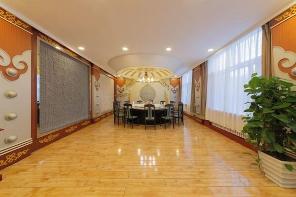 A hotel corridor with a dining area, large windows, and a chandelier.