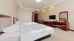Une chambre d’hôtel avec deux lits, un bureau, une télévision et un miroir.