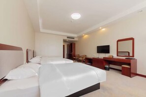 A hotel room with two beds, a desk, a television, and a mirror. - Ujimqin Hotel (West Ujimqin Banner)