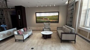 Un salon moderne avec un grand tableau, deux canapés, une table basse et un mur orné d’un motif.