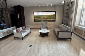 A modern living room with a large painting, two sofas, a coffee table, and a patterned wall. - Ujimqin Hotel (West Ujimqin Banner)