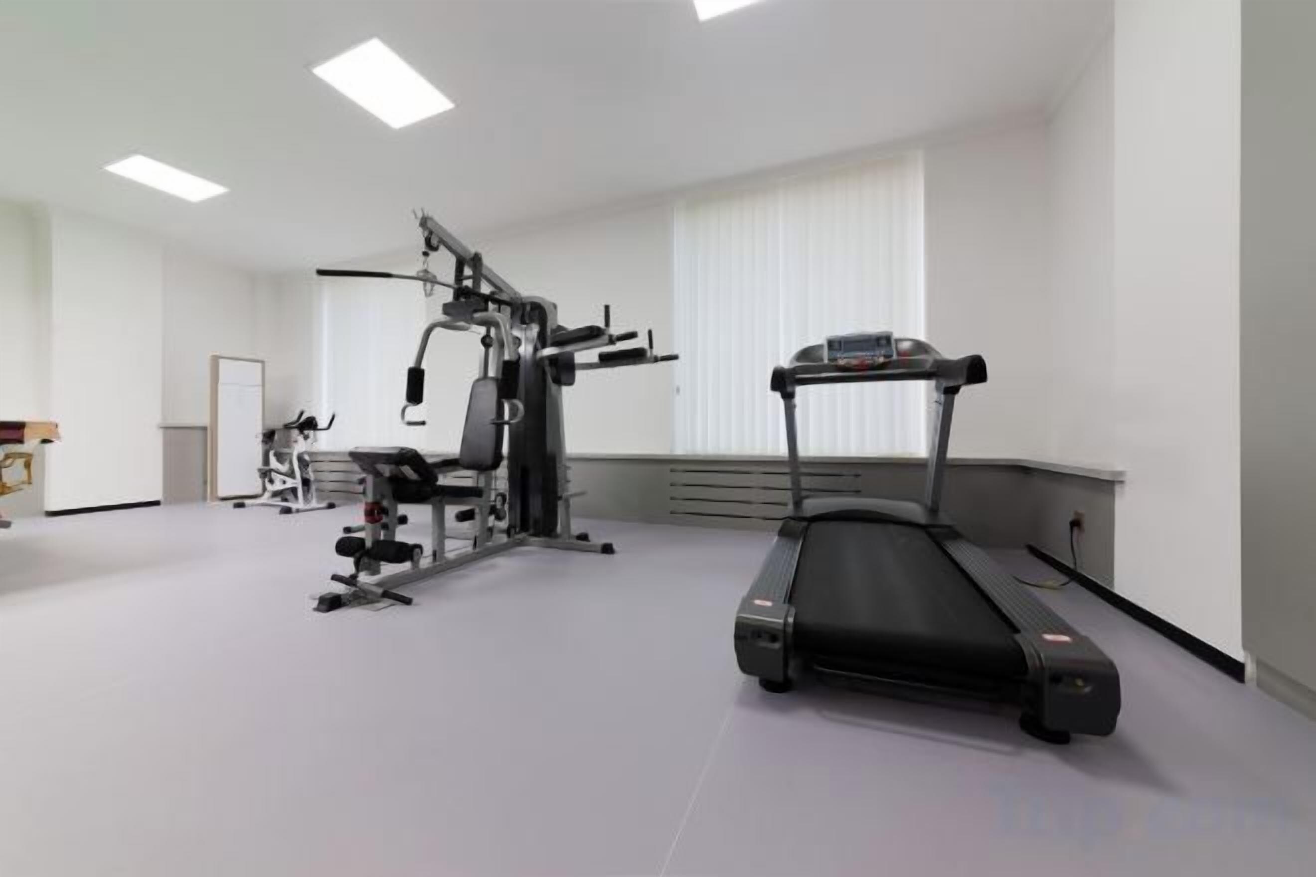 A gym with a treadmill, weight machines, and a bench.