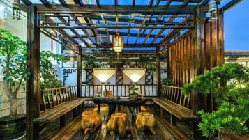 A wooden deck with a table and benches, surrounded by potted plants and a wooden railing.